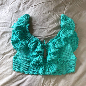 A teal, frilly crochet top (the Juniper Top) is laid out on a neutral background.