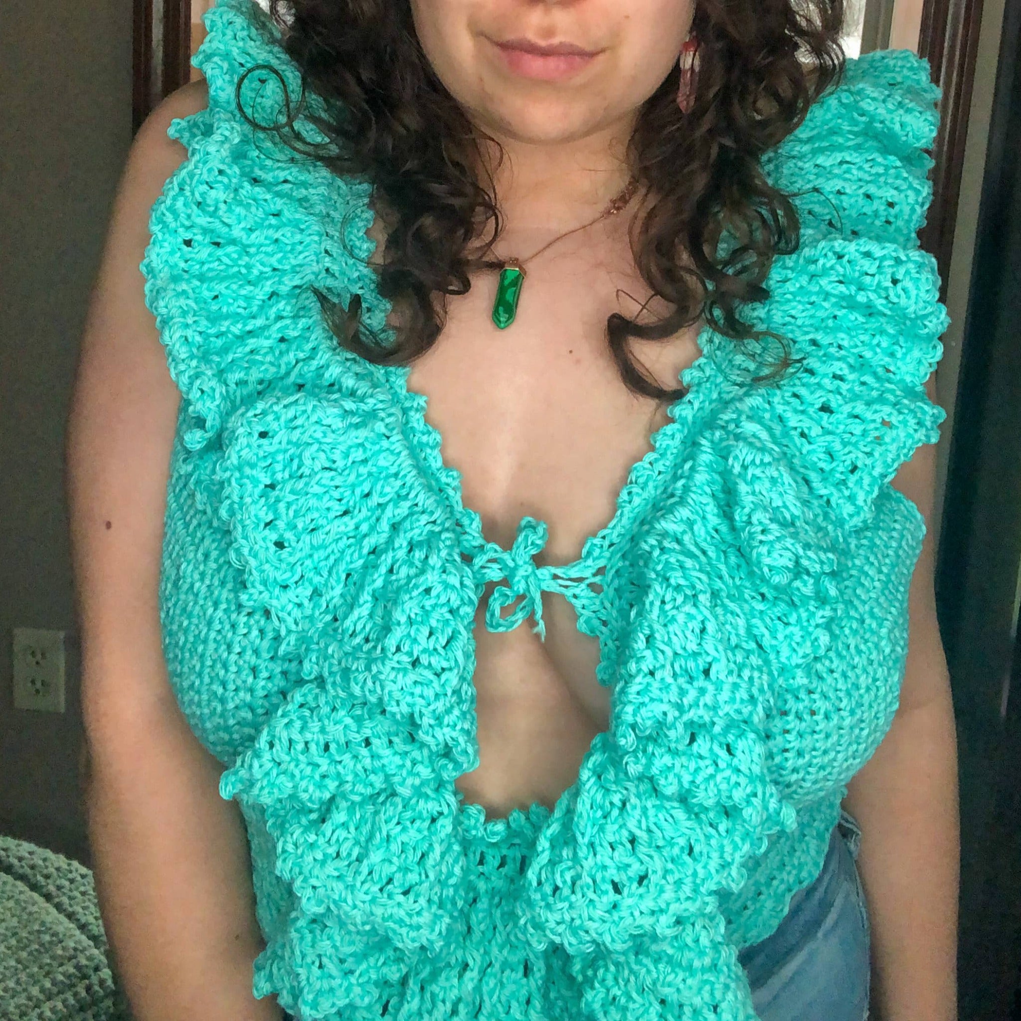 A woman with brown curly hair models the Juniper Top in teal.