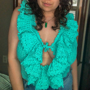 A woman with brown curly hair models the Juniper Top in teal. 